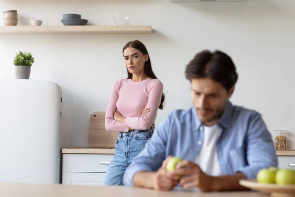 Offended sad european millennial woman looks at unhappy husband after quarrel at kitchen interior - Foto, Imagen