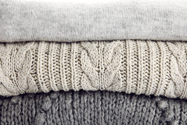 Pila de suéteres grises de moda como fondo - Foto, Imagen