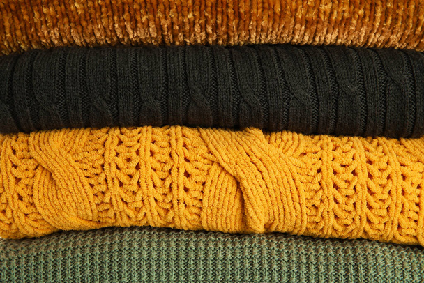 Pila de diferentes suéteres con estilo como fondo - Foto, Imagen