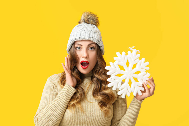 Shocked woman with snowflake on yellow background - Φωτογραφία, εικόνα