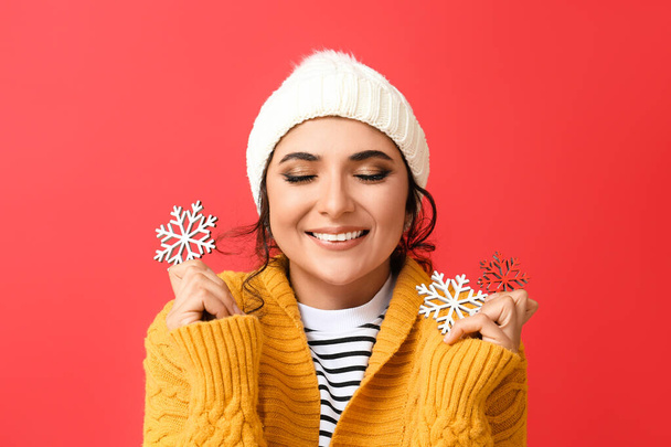 Happy woman with closed eyes holding beautiful snowflakes on red background - Photo, Image