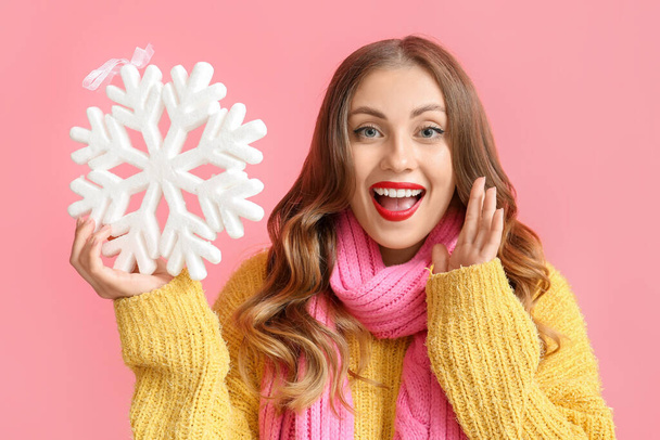 Emotional woman holding big snowflake on color background - Photo, Image