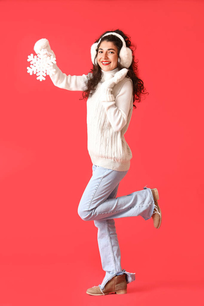 Mooie wandelende jonge vrouw met sneeuwvlok op kleur achtergrond - Foto, afbeelding