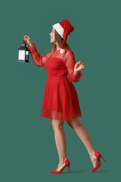 美しいサンタの帽子と提灯の色の背景で若い女性を歩く - 写真・画像