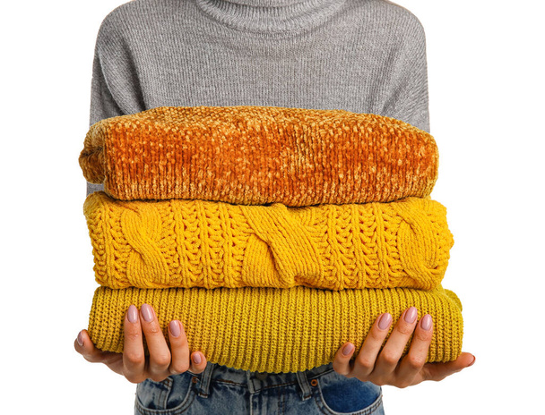 Женщина держит стопку вязаных свитеров на белом фоне - Фото, изображение