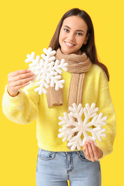 Beautiful woman in warm scarf with big snowflakes on yellow background - Zdjęcie, obraz