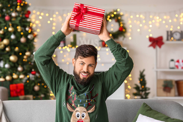 Happy man with Christmas gift at home - Фото, изображение