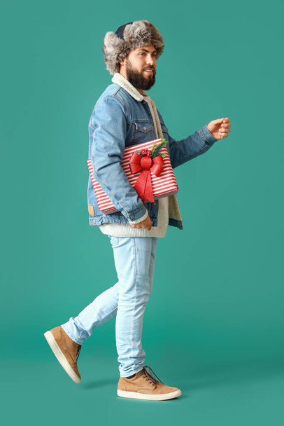 Walking man with Christmas gift on color background - Foto, Imagem