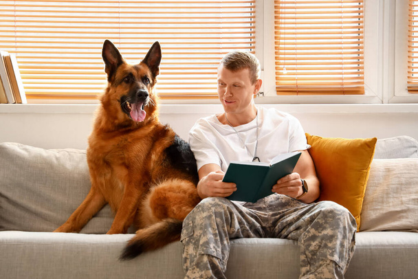 Soldier of USA army with military working dog reading book at home - Фото, зображення