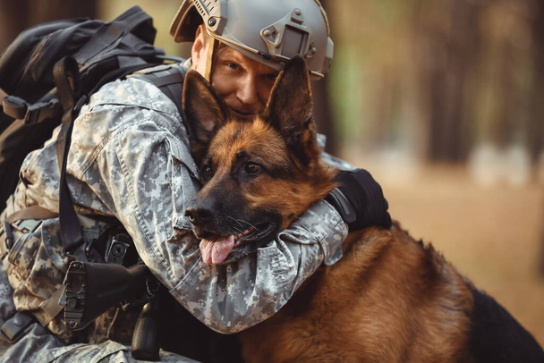 Soldado abrazando perro de trabajo militar al aire libre - Foto, Imagen