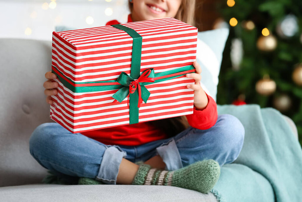 Cute little girl with gift at home on Christmas eve - Photo, Image