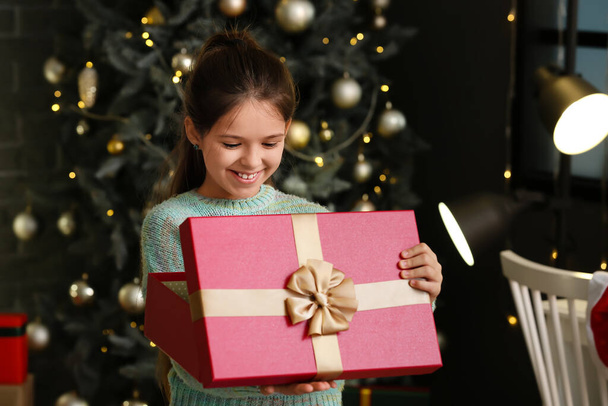 Cute girl opening Christmas gift at home - Foto, Bild