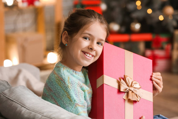 Cute little girl with gift at home on Christmas eve - Foto, imagen