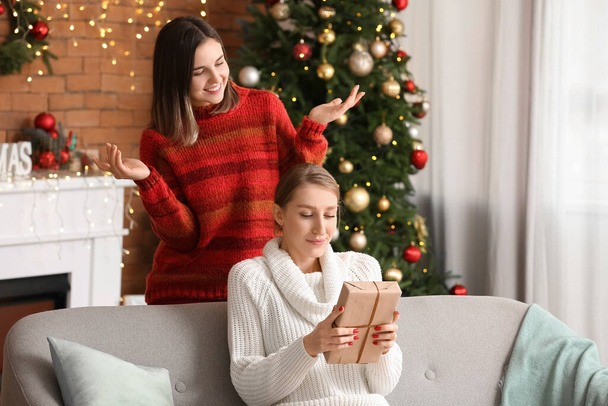 Молодая женщина приветствует своего друга в канун Рождества дома - Фото, изображение