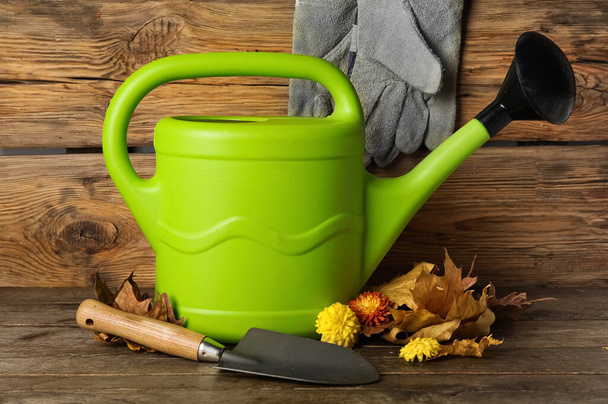 Watering can with beautiful Chrysanthemum flowers and shovel on wooden background - Foto, Bild