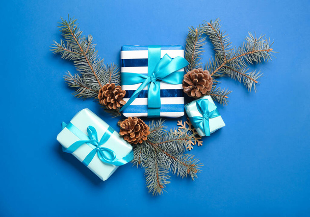 Χριστουγεννιάτικη σύνθεση με κουτιά δώρων, κουκουνάρια και κλαδιά ελάτης σε μπλε φόντο - Φωτογραφία, εικόνα