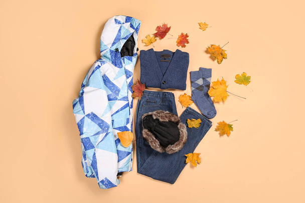 Chaqueta masculina cálida, sombrero, chaqueta, calcetines, jeans y hojas de otoño sobre fondo de color - Foto, Imagen