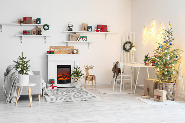 Interior of light living room with fireplace, Christmas trees and glowing lights - Photo, Image
