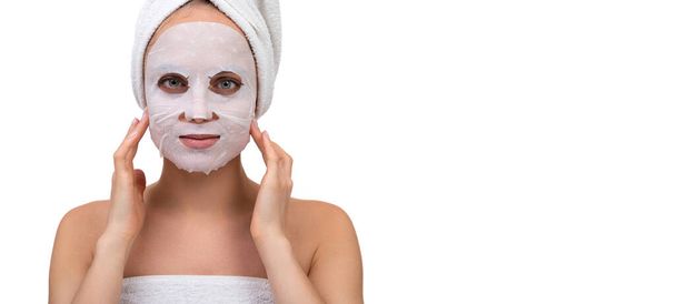 una mujer después de una ducha con una máscara cosmética blanca en la cara masajea la piel alrededor de los pómulos - Foto, Imagen