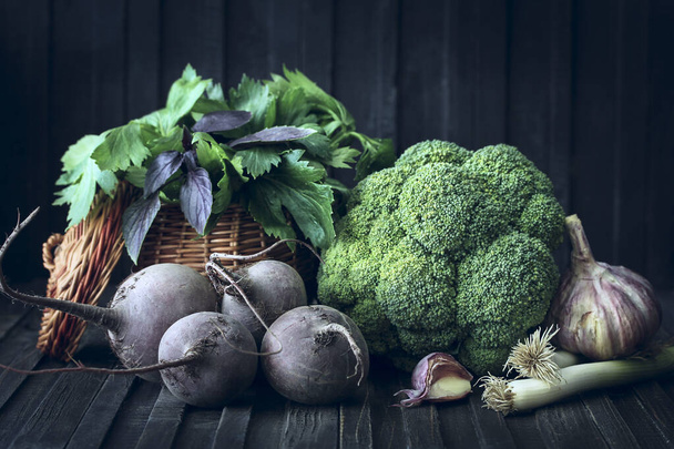 Harvest. Vegetables in a basket on a wooden background. Rustic. Fresh broccoli cabbage, garlic, basil, parsley, beetroot and onion. Background image, copy space - Foto, imagen