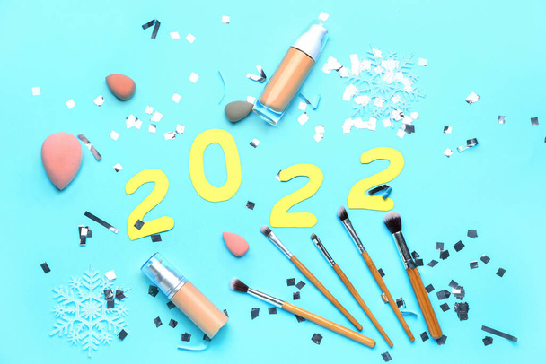 Figura 2022 con rifornimenti di trucco e coriandoli sullo sfondo di colore - Foto, immagini