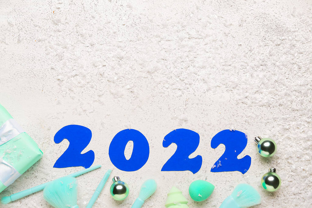 Kuva 2022 meikkitarvikkeilla ja lumella valkoisella pohjalla - Valokuva, kuva