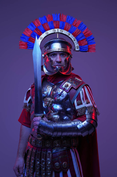 Výstřel starověkého římského vojáka pózujícího v barevném tmavém světle - Fotografie, Obrázek