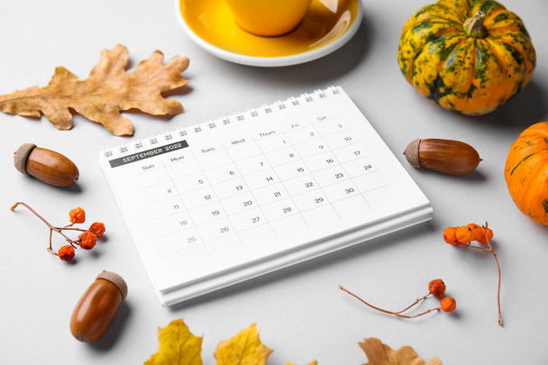 2022年9月の古典的なフリップペーパーカレンダー、グレーの背景にコーヒーと秋の装飾のカップ、クローズアップ - 写真・画像