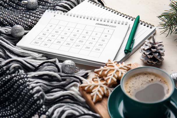 Papír naptár január 2022, csésze kávé, írószer kellékek és karácsonyi dekoráció könnyű fa asztalon - Fotó, kép