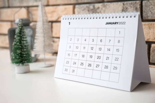 Ημερολόγιο χαρτιού για τον Ιανουάριο 2022 στο ράφι κοντά στον τοίχο τούβλο, closeup - Φωτογραφία, εικόνα
