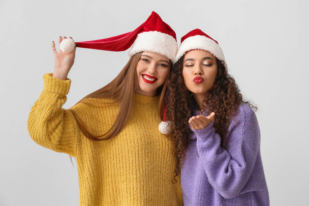 Belles jeunes femmes en chapeaux de Père Noël sur fond clair - Photo, image