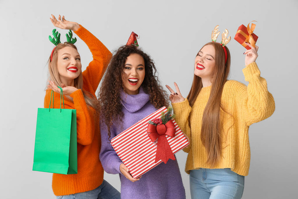 Beautiful young women with Christmas gifts on light background - Photo, Image