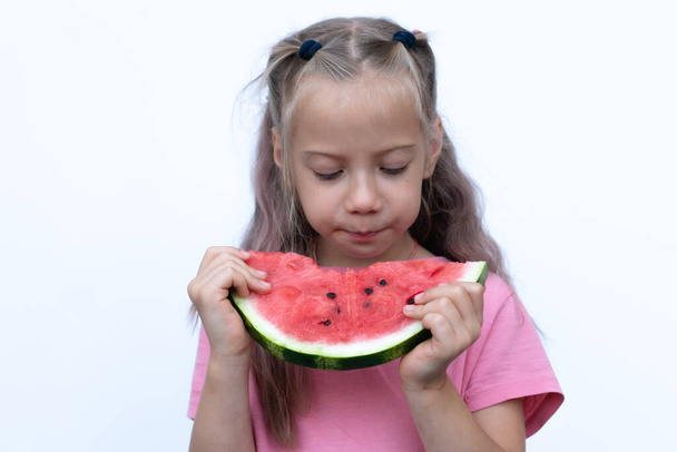 portret dziewczynki jedzącej arbuza, stojącej w różowej koszulce - Zdjęcie, obraz