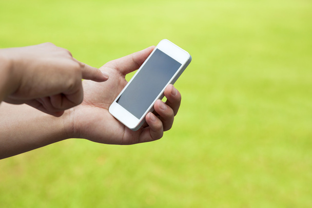 touch screen mobiele telefoon in de hand met groene weide - Foto, afbeelding