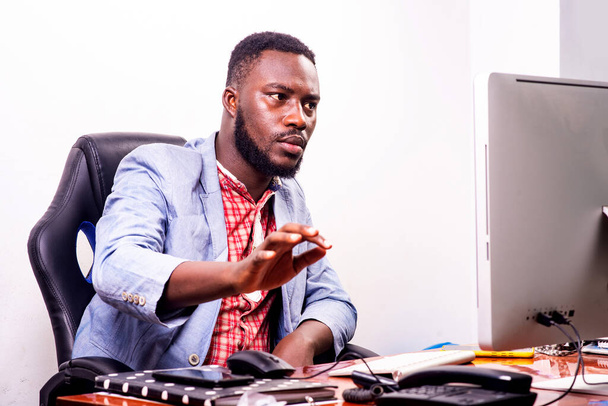 young serious businessman sitting and working with laptop in office. - Photo, Image