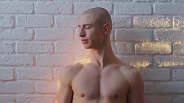 Jeune homme homosexuel chauve torse nu posant sur le mur blanc. Concept d'expression de la sexualité - Séquence, vidéo