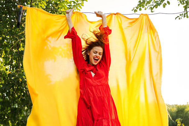 beautiful woman posing in red dress outdoors yellow cloth - Photo, Image