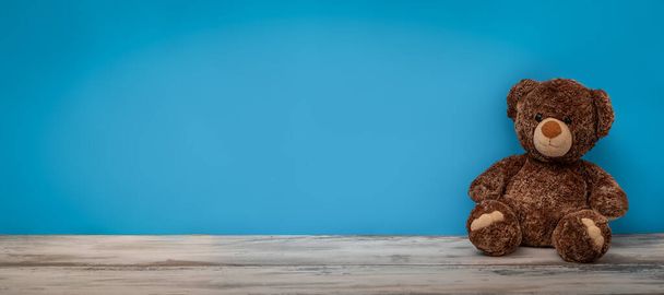 A stuffed bear toy isolated on a blue wall background - Photo, Image