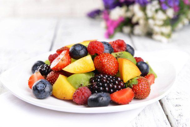 Вкусный фруктовый салат в тарелке на столе крупным планом - Фото, изображение