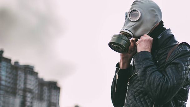 man in a gas mask walking through a city Parking lot - Фото, изображение