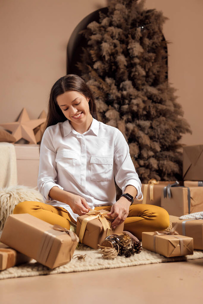 Młoda kobieta pakuje prezenty świąteczne na święta - Zdjęcie, obraz