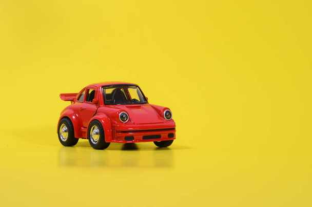 Um carro de brinquedo vermelho em um fundo amarelo - Foto, Imagem