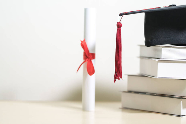 A closeup of a mortarboard and degree certificate on a white table in an education concept - 写真・画像