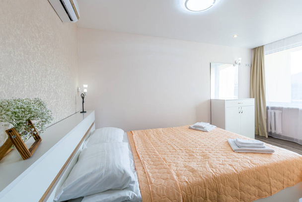Interior of a bedroom with white walls and a large double bed with a white blanket in the hotel - Foto, Imagem