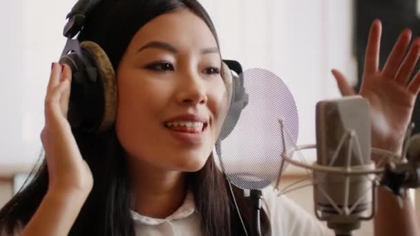 Processus de production de chansons. Chanteuse asiatique enregistrant une nouvelle piste dans un studio de musique - Séquence, vidéo