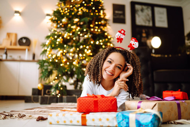 Portrait of happy woman celebrating winter holidays with large gift boxes near Christmas tree. Christmas surprise. - Fotoğraf, Görsel