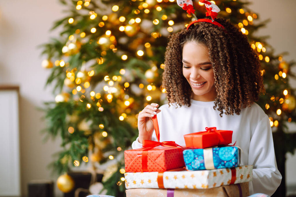 Portrait of happy woman celebrating winter holidays with large gift boxes near Christmas tree. Christmas surprise. - Valokuva, kuva