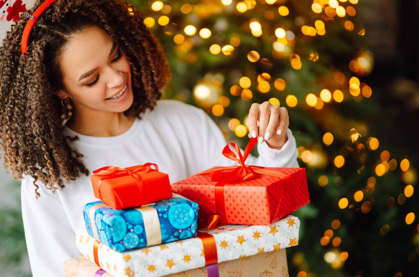 Portrait of happy woman celebrating winter holidays with large gift boxes near Christmas tree. Christmas surprise. - Φωτογραφία, εικόνα