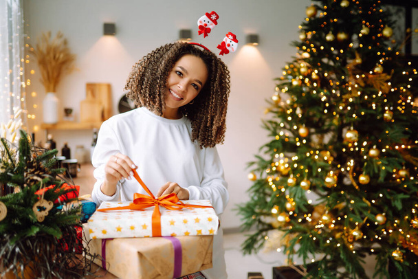 Portrait of happy woman celebrating winter holidays with large gift boxes near Christmas tree. Christmas surprise. - Foto, Imagen
