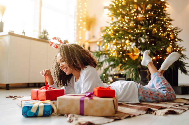 Retrato de una mujer feliz celebrando las vacaciones de invierno con grandes cajas de regalo cerca del árbol de Navidad. Sorpresa de Navidad. - Foto, Imagen